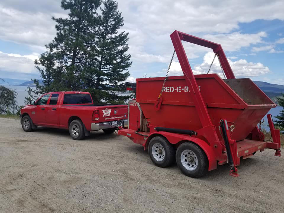 Red-E-Bins 15-yard dumpster placed on a roadside near a grassy, open area.