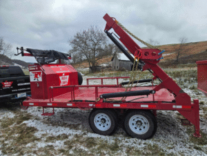 A Red-E-Bins hydraulic lift trailer parked on a rural property with light snow, showcasing its functionality for dumpster rental services in Bristol, VA